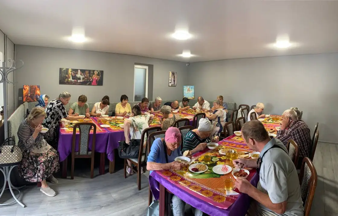 Відвідувачі соціальної їдальні за накритими столами