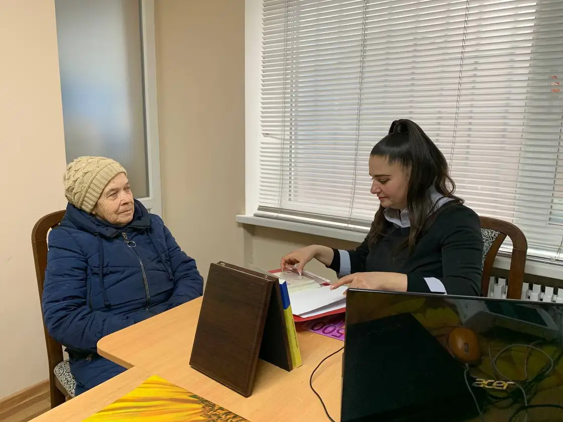 Оформлення допомоги: працівниця фонду за ноутбуком і відвідувачка