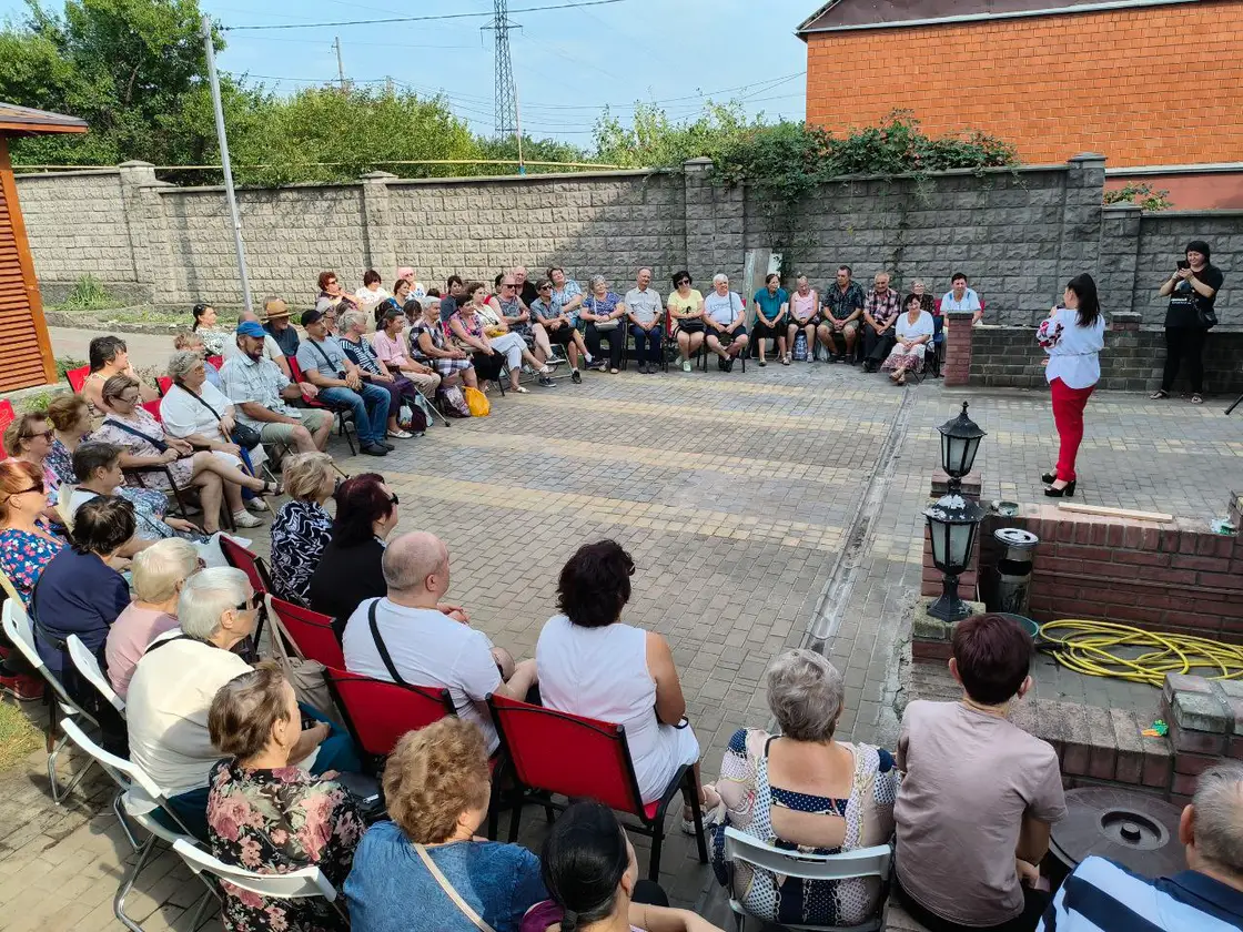 Захід на подвірʼї: люди на стільцях слухають виступ
