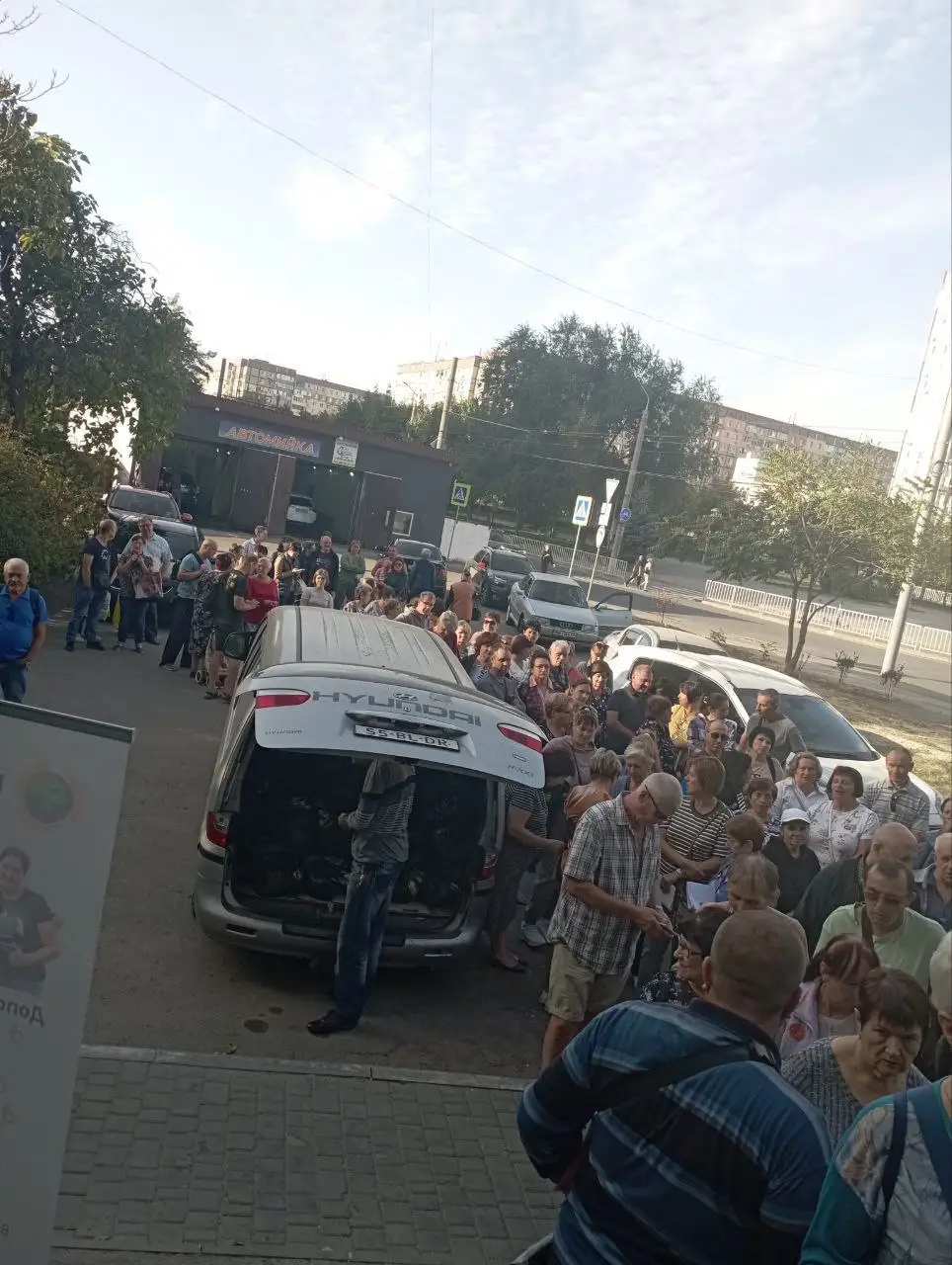 Черга людей біля автівки під час видачі допомоги