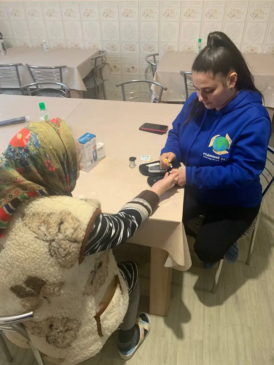 Працівниця фонду допомагає літній відвідувачці за столом