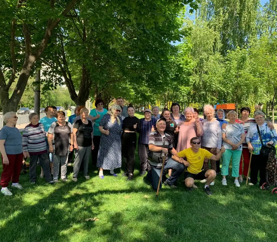 Літні люди на груповому фото серед дерев — проєкти фонду «Родинний Світ» у Дніпрі